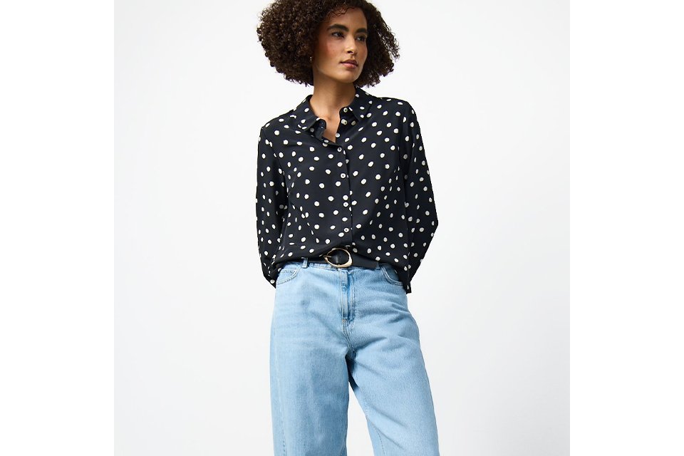Navy blue polka dot button-through blouse styled with light wash wide-leg jeans and a black belt for a smart casual look.
