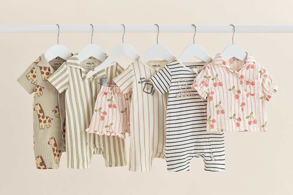 Children's swimwear set featuring a red gingham long-sleeve rash vest with strawberry applique, blue lobster-print swim shorts, and a striped strawberry-print ruffle swimsuit, displayed on a neutral background.