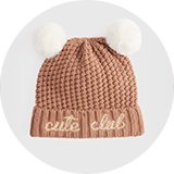 Pink baby pom-pom beanie with waffle-knit texture and embroidered "cute club" slogan.