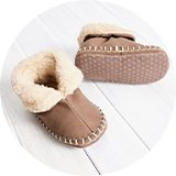 Taupe baby slippers with plush fleece lining and non-slip soles for cosy indoor comfort.