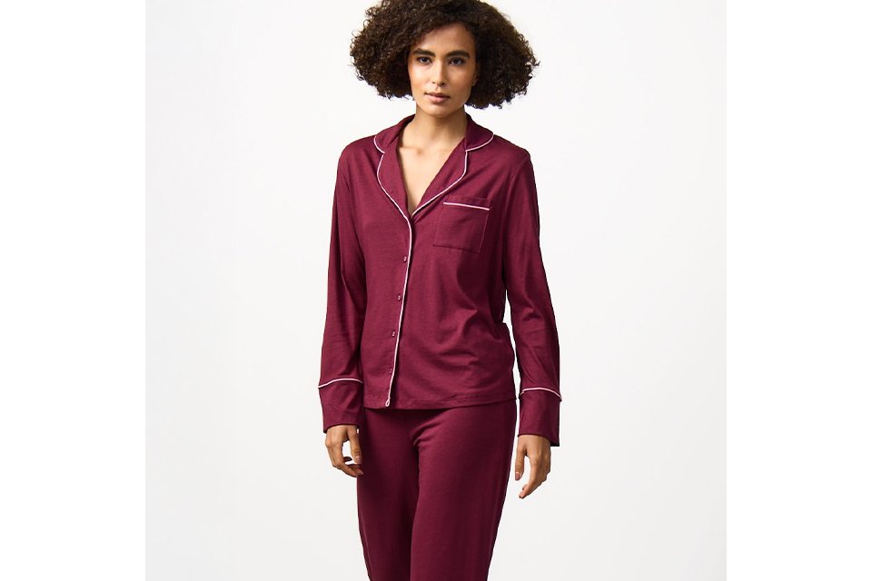 Women's satin pyjama set in burgundy with long-sleeve button-up top and matching trousers, comfortable coordinated nightwear.