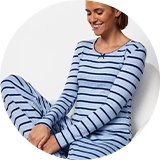 Light blue striped pajama set with matching lounge pants and grey slippers in a studio setting.