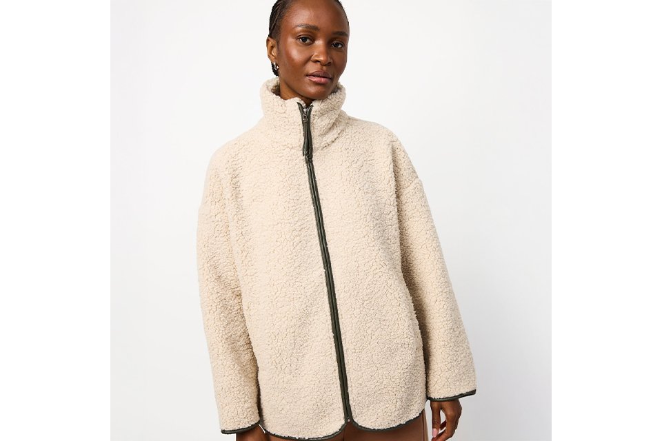 A woman wearing a borg, cream fluffy zip up jacket.