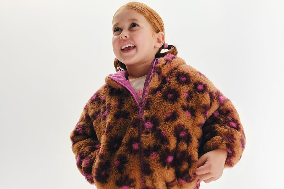 A young girl wearing a fluffy animal print jacket.