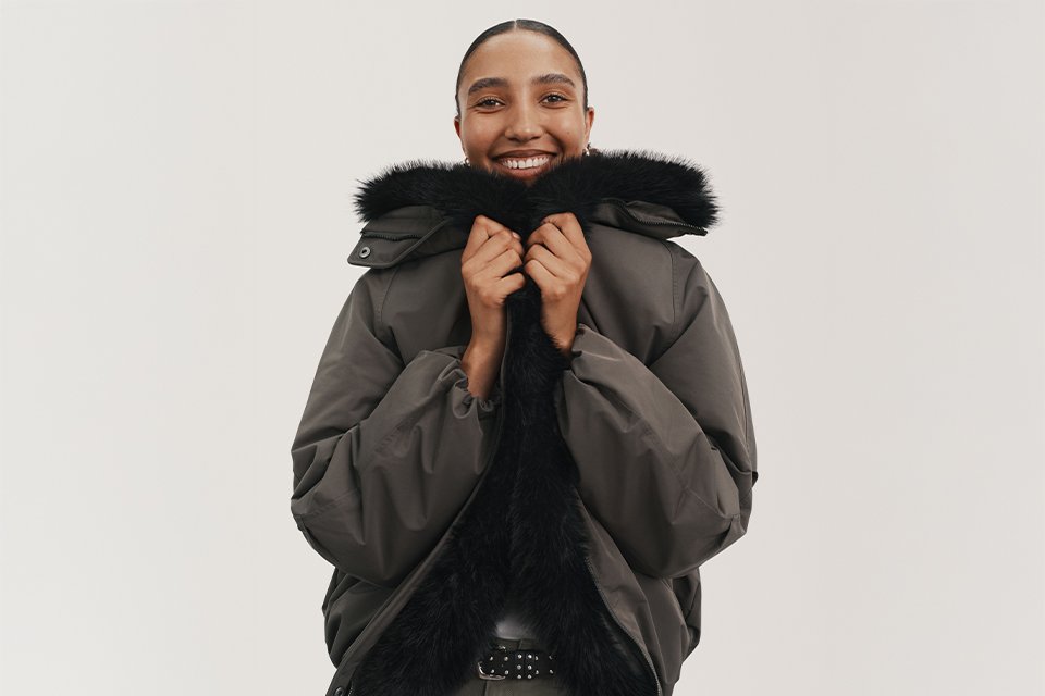 A woman wearing a pffa jacket with faux fur and khaki jeans.