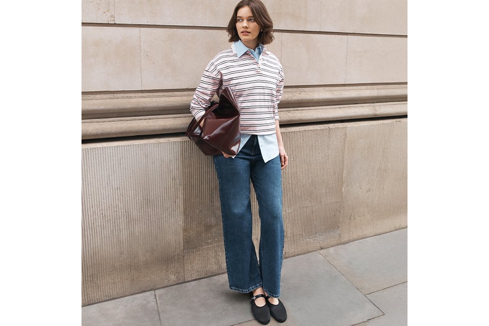 Striped rugby-style knit top layered over a blue collared shirt, paired with straight-leg denim jeans and black Mary Jane flats.