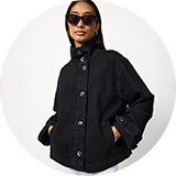 Black denim jacket with a high stand collar, button-front fastening, and side pockets, styled with sunglasses for a modern casual look.