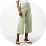 White sleeveless top paired with sage green cropped wide-leg trousers and sandals.