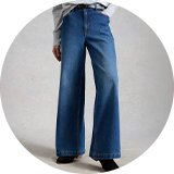 Blue high-waisted wide-leg jeans styled with a grey knit jumper and black ankle boots.