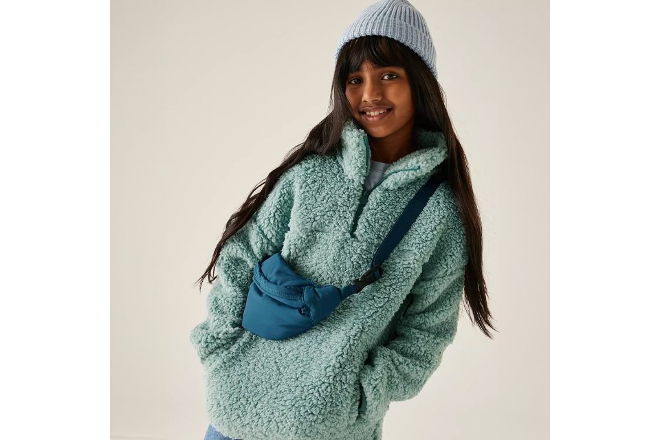 Girl wearing green fleece and blue hat.