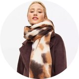 Stack of patterned winter scarves in neutral tones. 