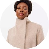 Woman wearing stone coloured funnel neck coat.