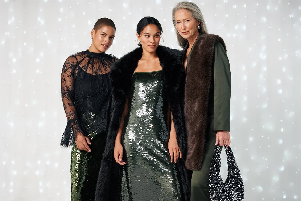 Three people in sequin outfits standing against a sparkling light backdrop.