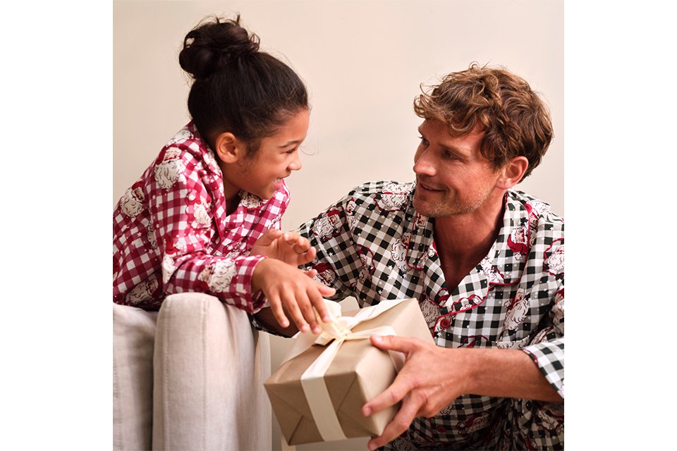 Family wearing matching novelty Christmas pyjamas with festive check prints and Christmas gift boxes.