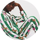 Model wearing green striped Disney Bambi Christmas pyjamas with festive reindeer, wreath and bauble prints.