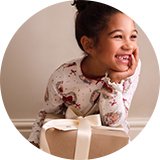 Child wearing festive Christmas pyjamas beside a Christmas Eve gift box.