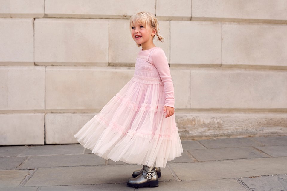 Girls' blush pink tiered tulle dress with long sleeves, smocked bodice and flowing maxi-length skirt.