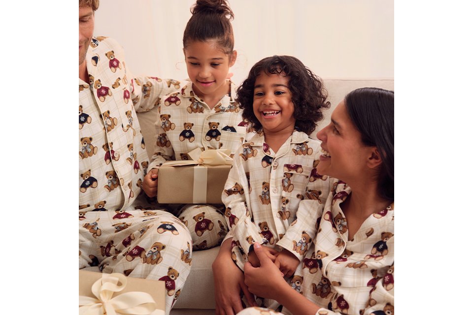 Family wearing matching Christmas pyjamas in festive seasonal prints.