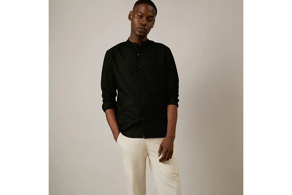 Men's black long-sleeve grandad collar shirt styled with cream trousers for a modern smart-casual outfit.
