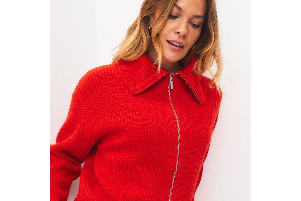 A woman wearing a bright red lambswool zir-through cardigan.