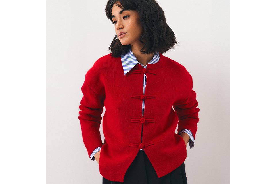 Woman wearing bright red cardigan with blue and white stripey shirt underneath.