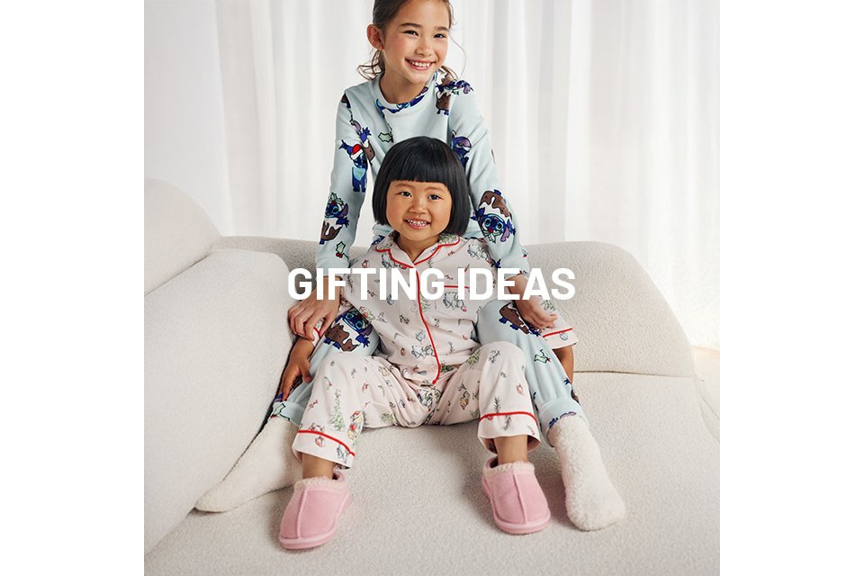 Two children wearing christmas pyjamas.