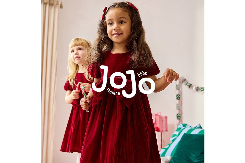 Two children wearing red velvet dresses with bows.