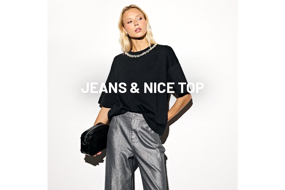 Woman wearing black embelisshed top and metallic jeans.