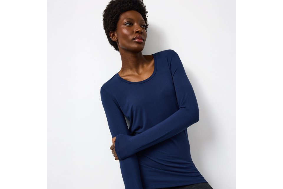 Person wearing a fitted, long-sleeve thermal top in dark navy blue, shown from the waist up against a plain background.