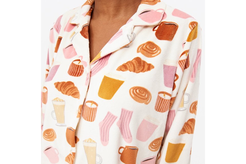 Woman wearing pyjama top with images of socks, tea, coffee and pastries like croissants.