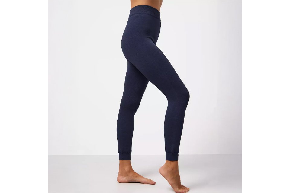 Person wearing slim-fit thermal leggings in dark navy blue, standing barefoot against a light background.