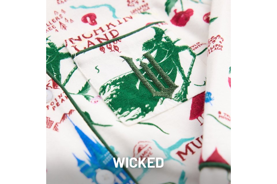 Close-up of fabric featuring green illustrations and red text inspired by the musical Wicked, with scattered decorative elements.