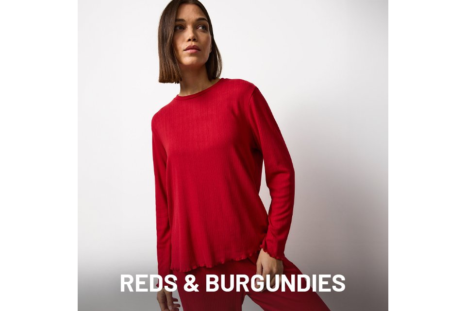 Person wearing a matching red ribbed loungewear set with a long-sleeve top and straight-leg pants against a plain white background.