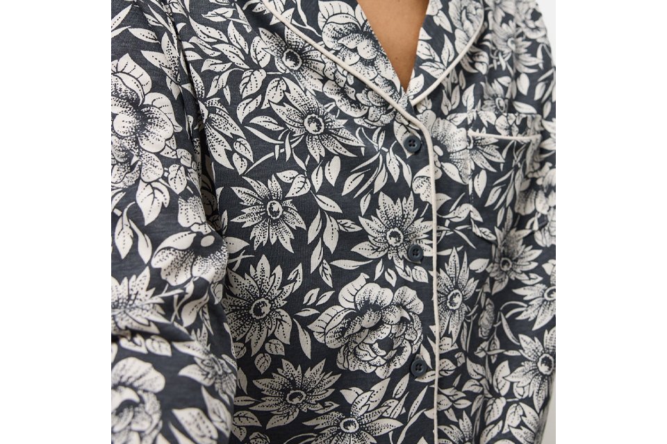 Woman wearing pyjama top with a black background and white flowers.