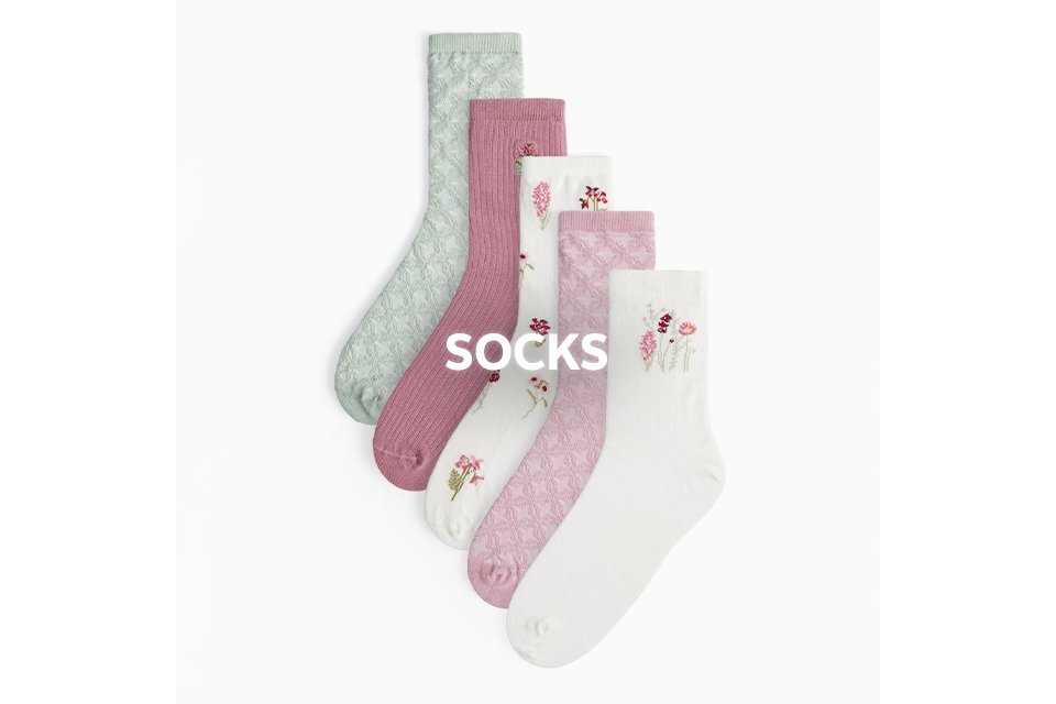 Assorted pastel socks in pink, white, and green with subtle patterns and small motifs. 