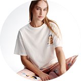 Person wearing a white short-sleeve top and patterned pyjama bottoms.