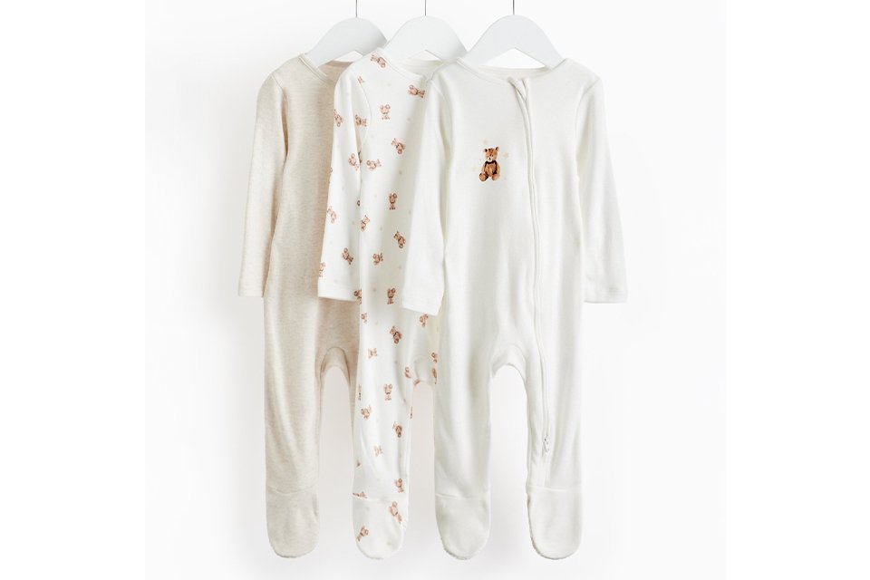 Unisex baby clothing featuring neutral-toned pajamas and playful essentials for newborns.