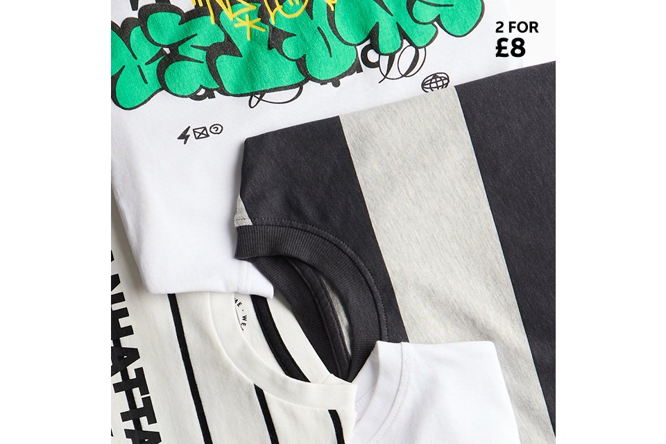 Assorted kids’ T-shirts featuring bold graphics, stripes, and colour‑block designs, shown in a flat lay.