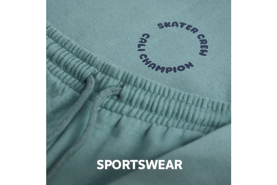 Close-up of green sportswear fabric with an elastic waistband and printed logo.