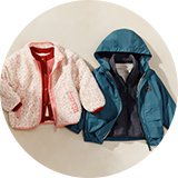 Selection of children’s coats laid out, including a pink faux‑fur coat, a blue hooded jacket, and a patterned coat.