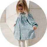 Child wearing a light blue long‑sleeve dress with ruffle details.