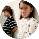 Children wearing new‑season clothing, including a striped top and a printed long‑sleeve shirt.