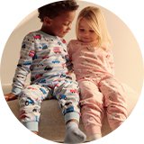 Two children sitting together wearing patterned pyjama sets.