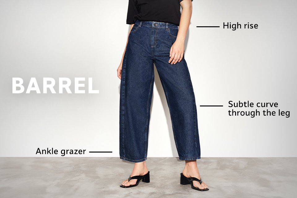 High-rise dark blue barrel jeans with subtle curve through the leg and ankle grazer length, styled with flat shoes. 