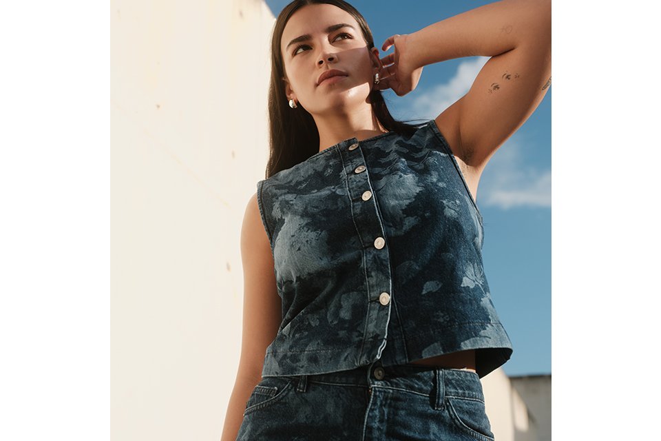 Close-up of a person wearing a dark denim jacket over a white top, styled with a blue patterned neck scarf.