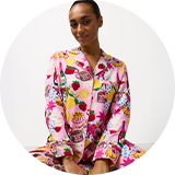 Person wearing a white short-sleeve top and patterned pyjama bottoms.