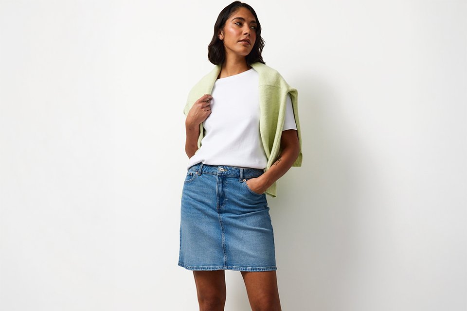Capsule travel outfit with white T-shirt, wide-leg trousers and lightweight green layer for a city break.