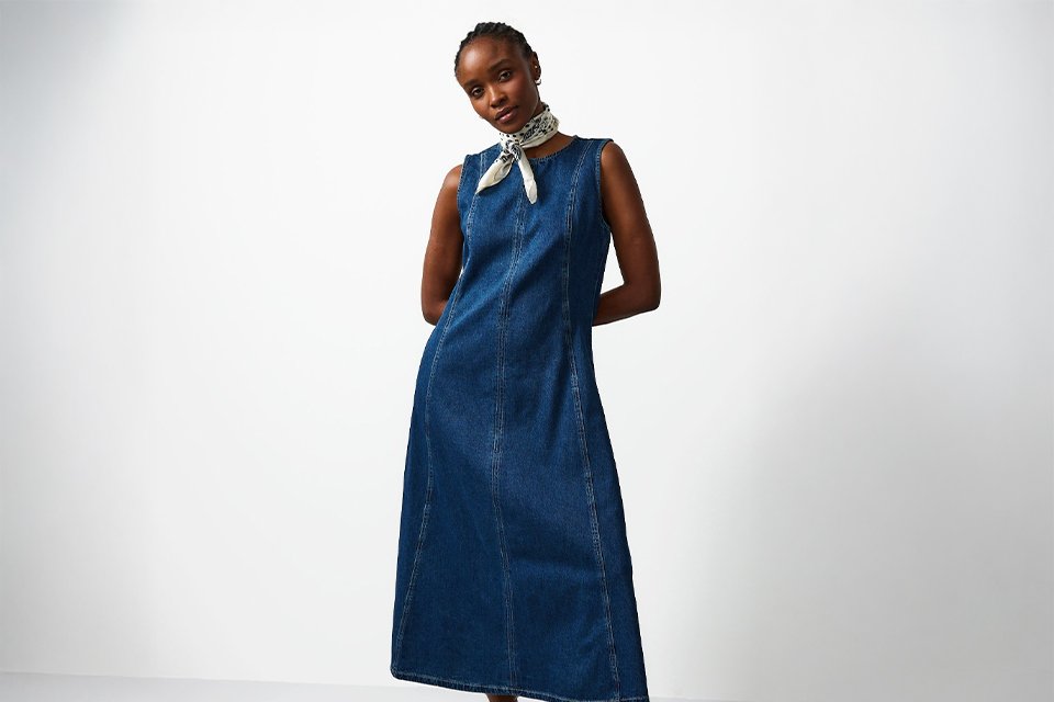  Casual wedding guest outfit featuring a sleeveless denim midi dress styled with statement accessories for a relaxed daytime wedding.